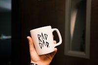 a person holding up a coffee mug with the word dad on it