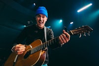 a man with a blue beanie playing an acoustic guitar