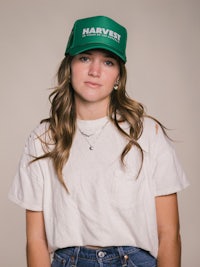 a young woman wearing a green harvest trucker hat