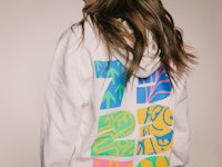 the back of a woman wearing a white hoodie with colorful designs