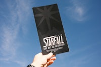 a person holding up a black and white starfall brochure