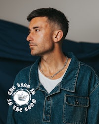 a man wearing a denim jacket in front of a blue background